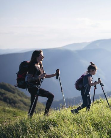 Mother and her daughter hiking in the mountains at sunset.